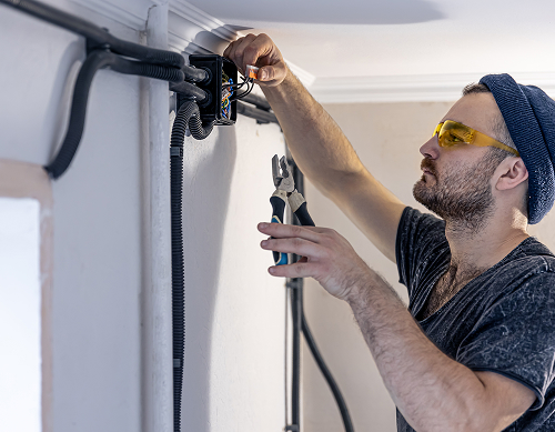 electrician is mounting electric sockets white wall indoors